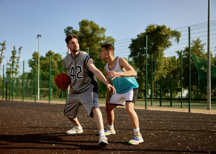 Active men playing basketball on street court. Sports and hobby recreation for friends on weekend